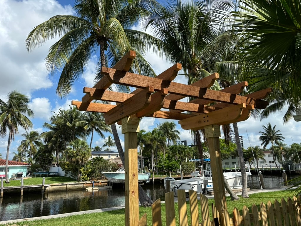 Completed pergola trellis structure by waterfront with palm trees